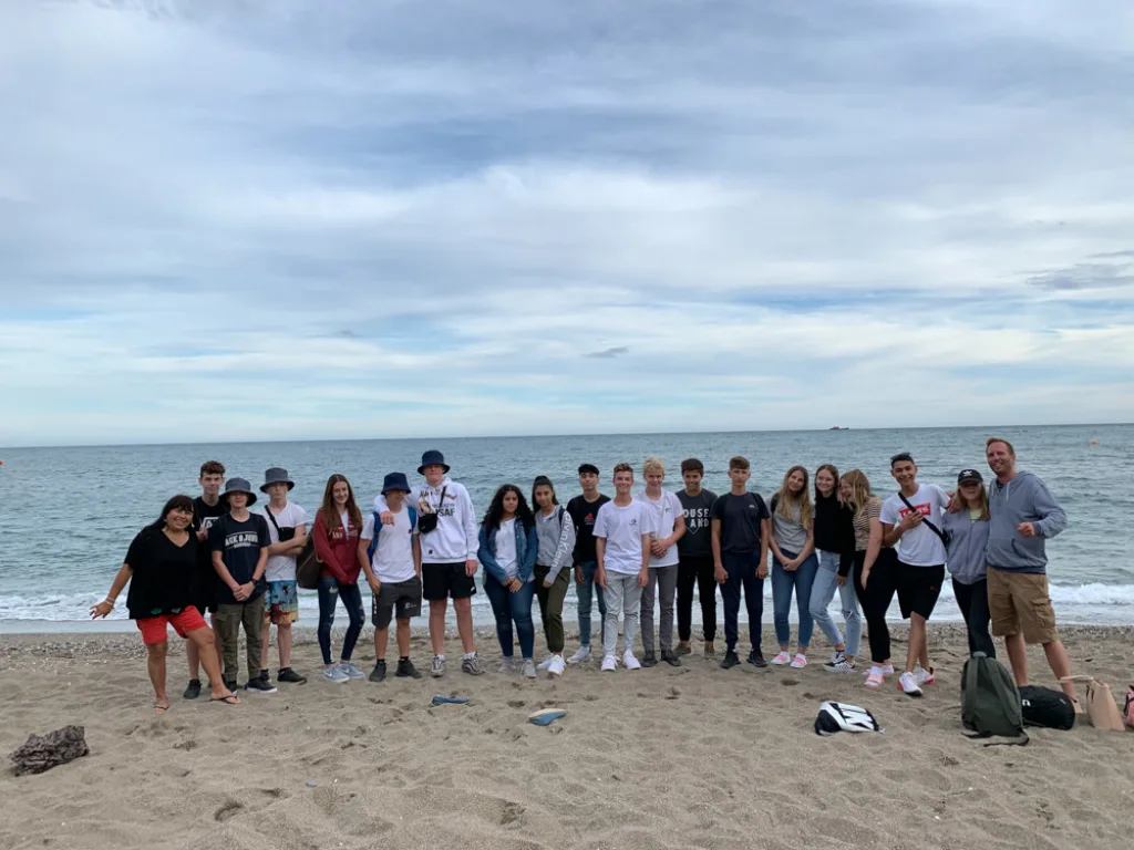 Die Gruppe steht am Strand vor dem Meer.